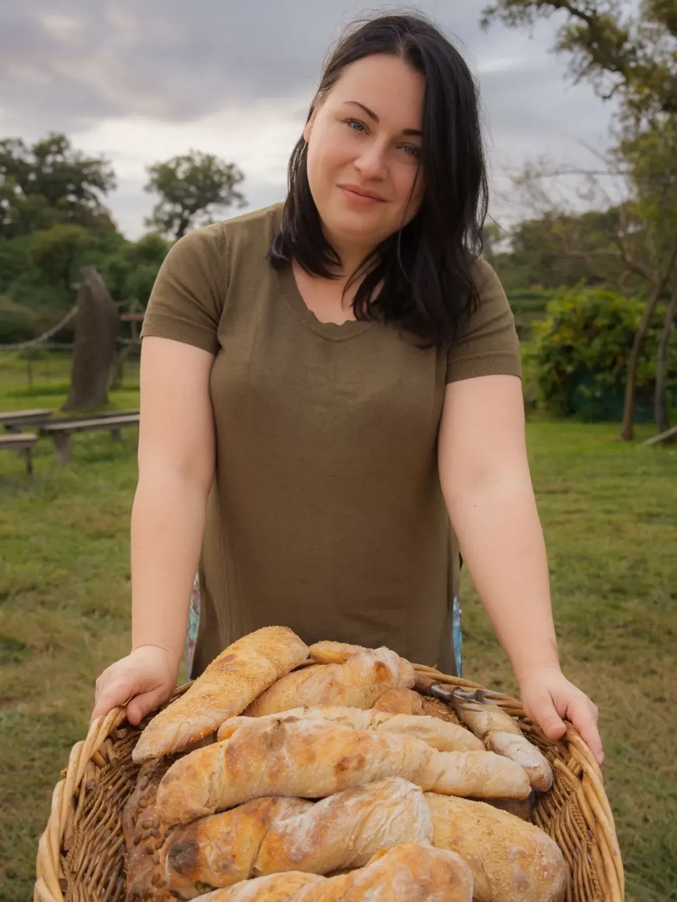 The baker outdoors holding a basket of fresh loaves